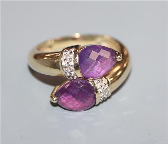 A modern 14k yellow metal and two stone amethyst crossover ring, size N/O.